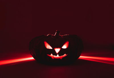 Close-up of illuminated red pumpkin against dark background