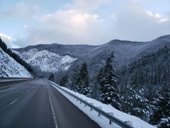 Road amidst snowcapped mountains against sky