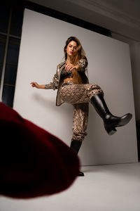 Portrait of young woman standing against wall