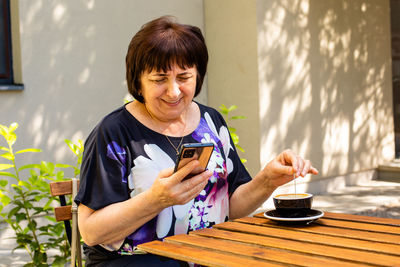 Young man using mobile phone while sitting on table