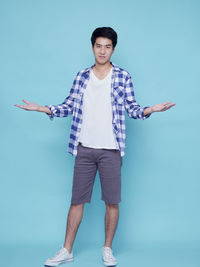 Portrait of young man standing against blue background