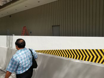 Rear view of boy walking against built structure