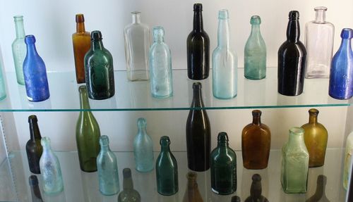 Close-up of various glass bottles on shelves against wall