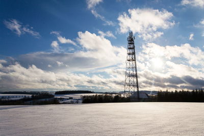 Communications tower on field against sky