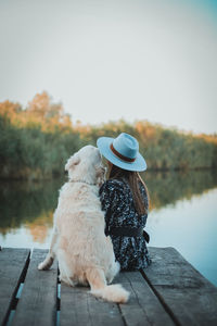 Rear view of woman and her dog standing on a pier