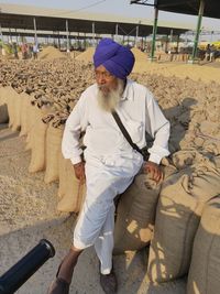 Mature man wearing turban sitting on sack at warehouse