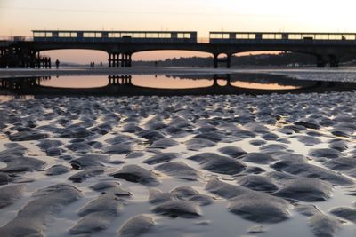 Bridge over sea against sky during sunset