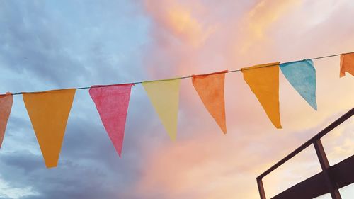 Low angle view of colorful buntings against cloudy sky during sunset