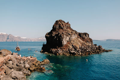 Rock formations in sea against clear blue sky