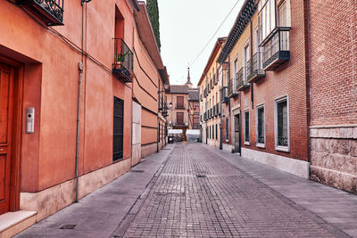 Alley amidst houses against sky