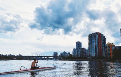 Man and woman on boat in river against sky