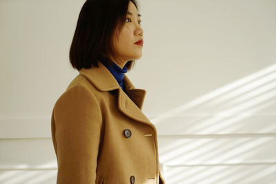 Close-up of young woman standing against white background