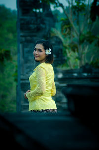 Young woman looking away while standing on plant