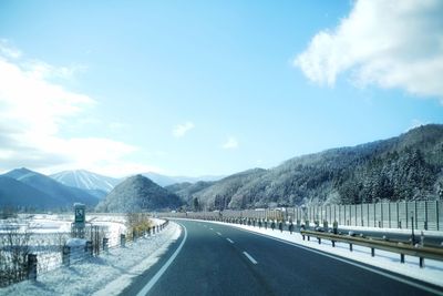 Road by mountains against sky