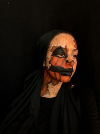 Portrait of woman wearing mask against black background