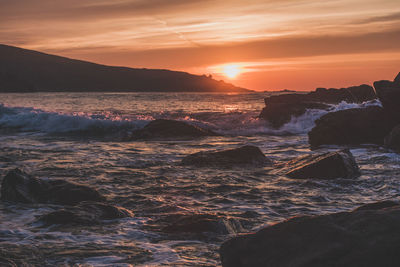 Scenic view of sea against dramatic sky during sunset