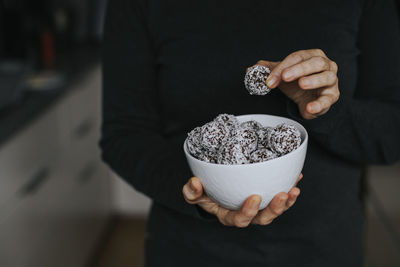 Woman's hands holding bowls with coconut balls