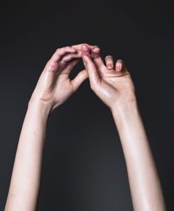 Cropped hands of woman against black background