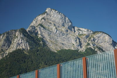 Low angle view of rocky mountains against clear blue sky