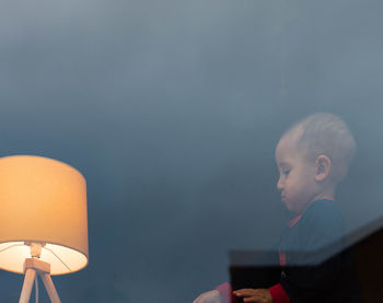 Portrait of boy looking at illuminated lamp