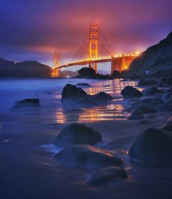 Illuminated golden gate bridge over bay at night