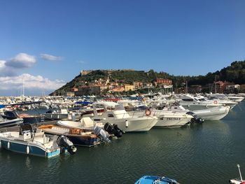 Sailboats moored in harbor against blue sky