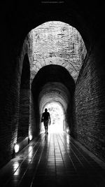 Rear view of woman walking in tunnel