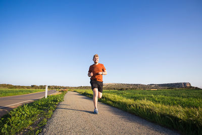 Full length of man on footpath against clear sky