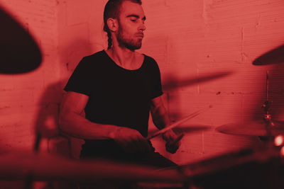 Group of musicians playing in red neon lights at music studio