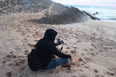 Rear view of man photographing on beach