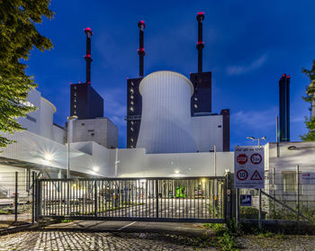 Illuminated factory against sky at dusk