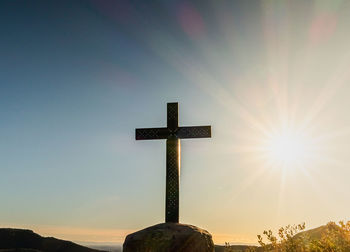 Cross in the top of a mountain with the sun in the background