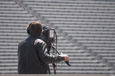 Man with television camera standing in stadium