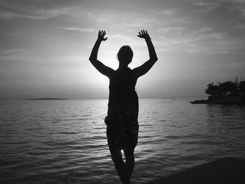 Silhouette of woman in sea at sunset