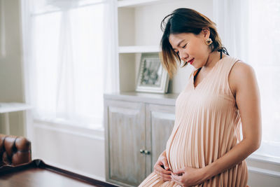 Woman looking away while standing against wall