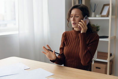 Frustrated businesswoman talking on phone in office