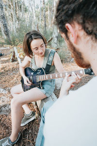 Girlfriend playing guitar sitting on forest