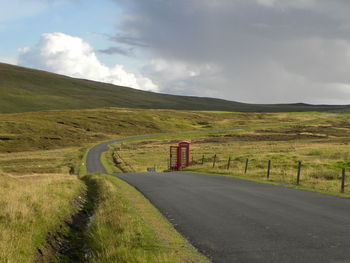 Road amidst field against sky
