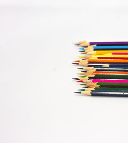 High angle view of multi colored pencils on table against white background