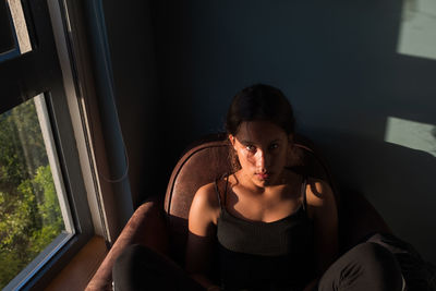 Portrait of young woman looking through window