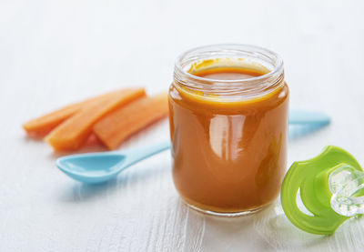Baby carrot mashed with spoon in glass jar, baby food