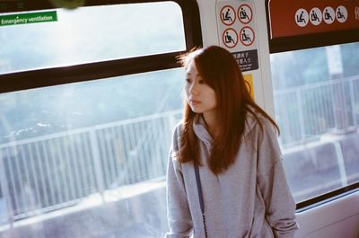 Thoughtful young woman standing by window in train