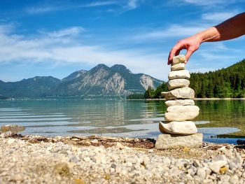 Balanced stone pyramide on shore of blue water of mountain lake. blue mountains in water mirror.