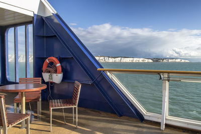 Chairs on table by sea against sky