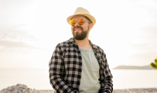 Young man wearing sunglasses while standing against sky