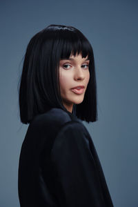 Portrait of young woman standing against blue background