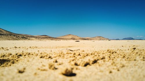 Scenic view of desert against clear blue sky