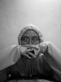 Portrait of girl holding camera against wall