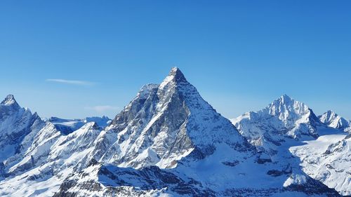 Scenic view of snowcapped mountains against clear blue sky