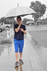 Full length of young man standing on wet rainy day